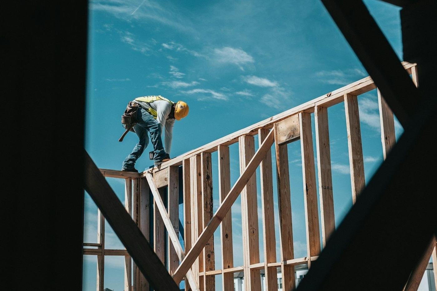 A builder framing a modern house against a blue sky