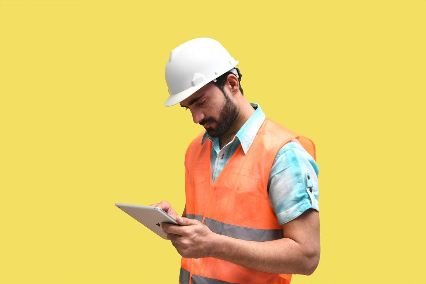 An engineer in a hard hat checking a tablet on site