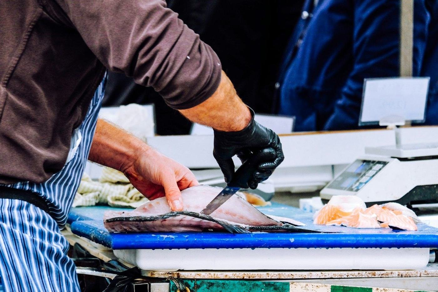 A worker filleting fish at a processing station
