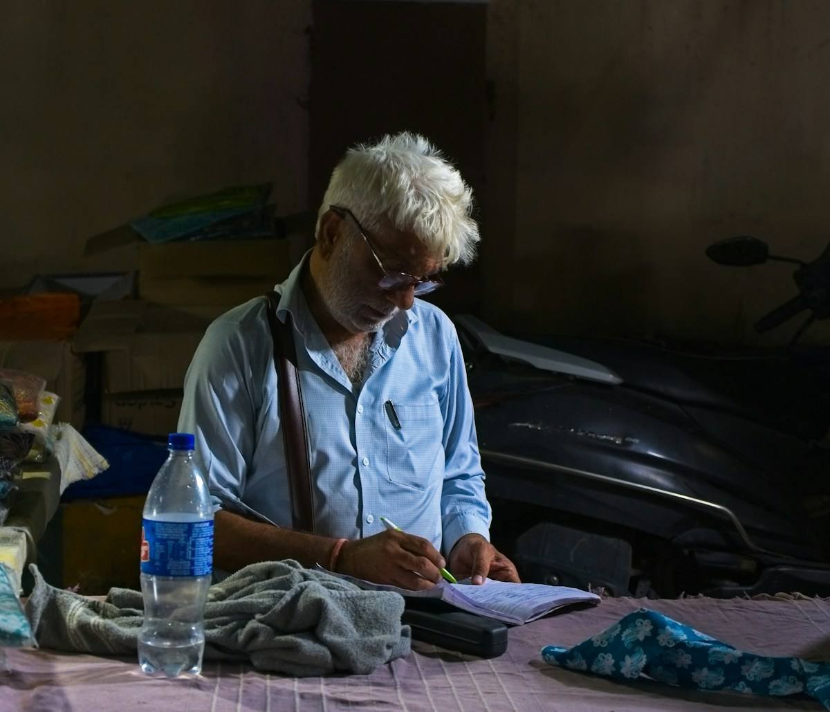 A cloth vendor writing in his ledger in India