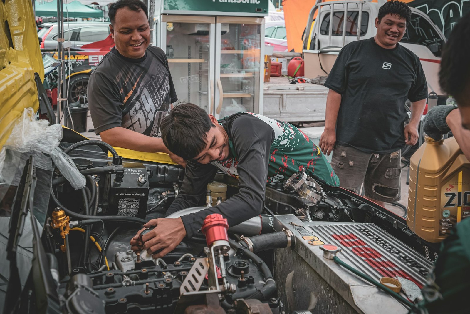 A repair-shop owner and his mechanics servicing an engine together