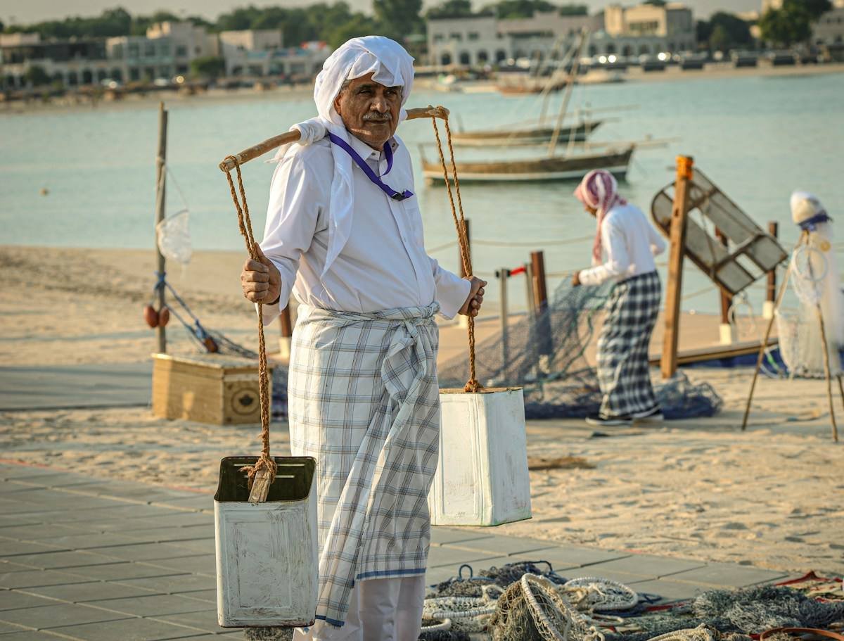 A worker carrying buckets on the shore in Qatar