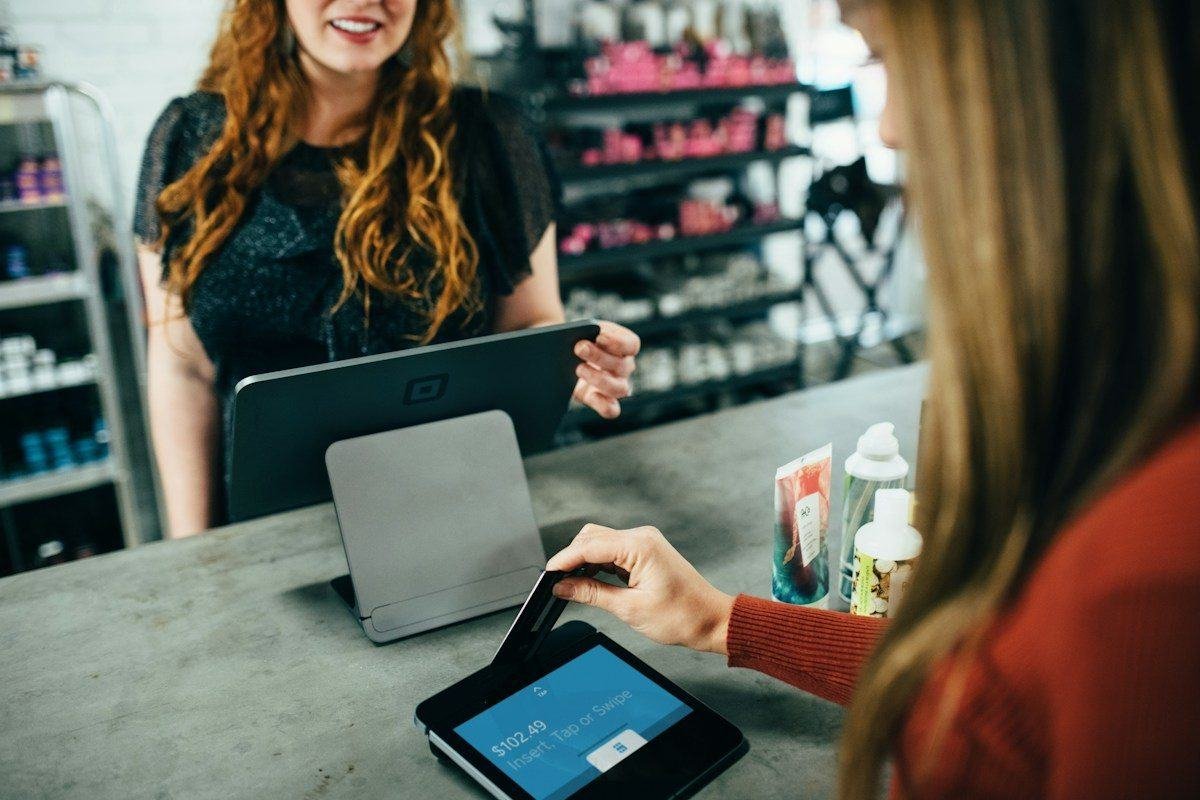 A shop owner using a tablet point-of-sale with a customer